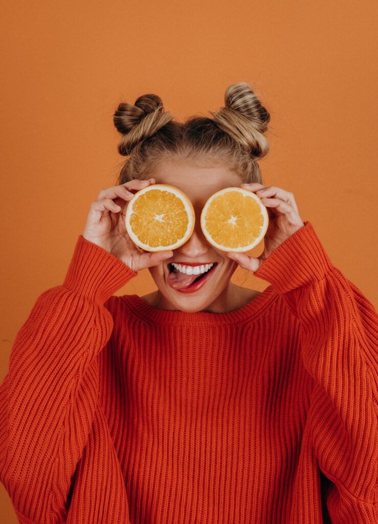 This picture describe a SEO professional girl in orange background with oranges on her eyes  